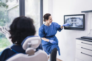 Female dentist explaining tooth x-rays to a unrecognizable patient.