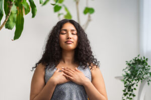 A beautiful and young multiracial woman is doing breathing exercise at home.