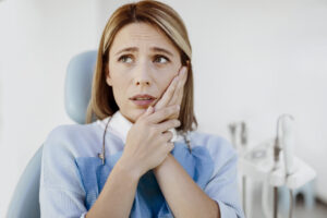 Woman complaining on toothache at the clinic. Symptoms of gums pain